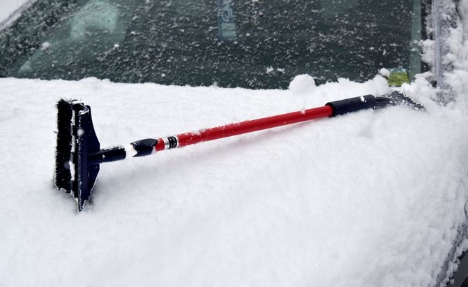subzero brand snow brush on a snow covered car hood