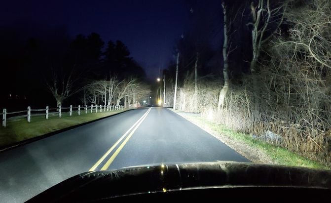 rural road at night illuminated brightly by headlights 